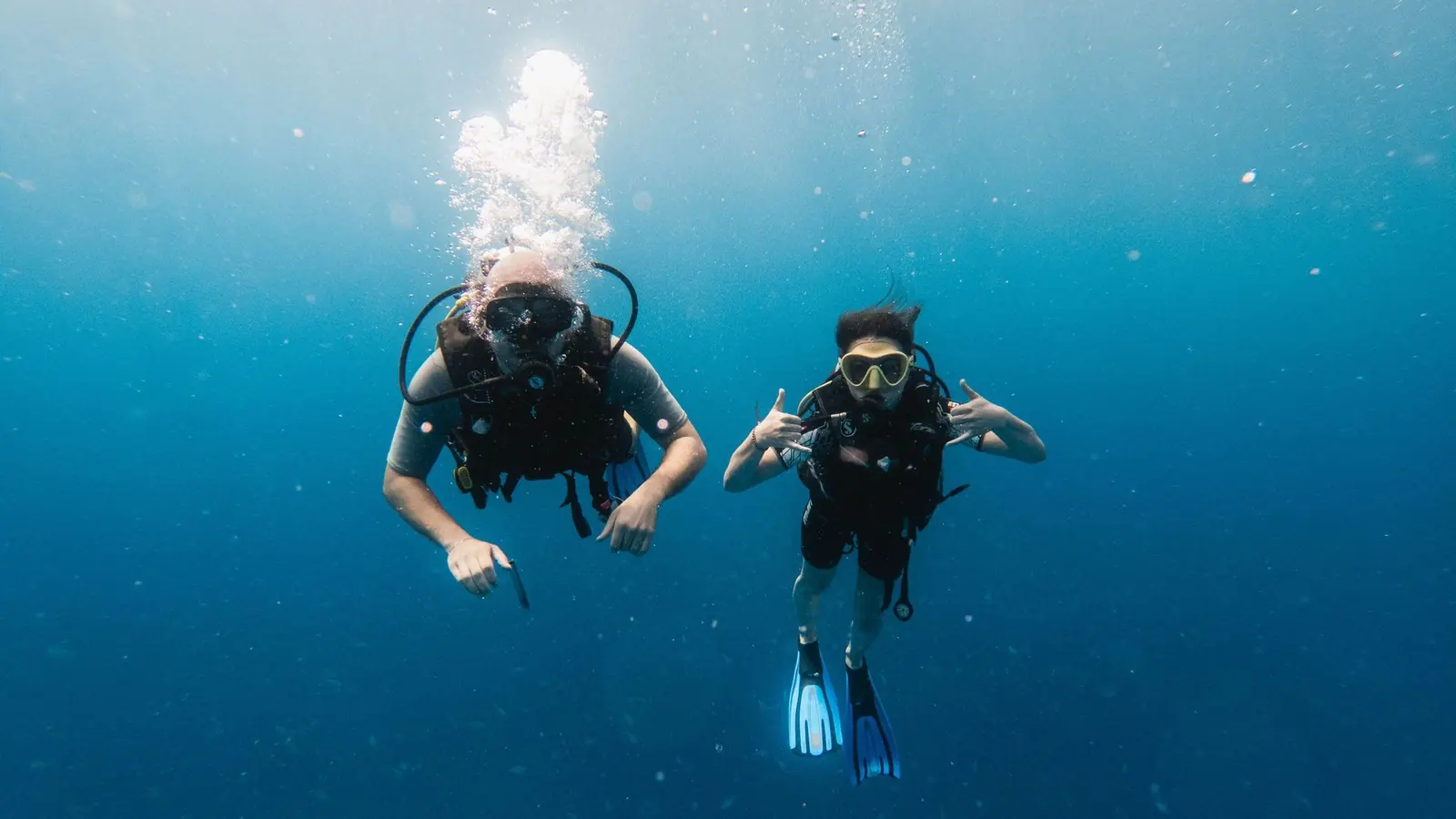 Dos buzos en el azul del mar hacen la seña de OK