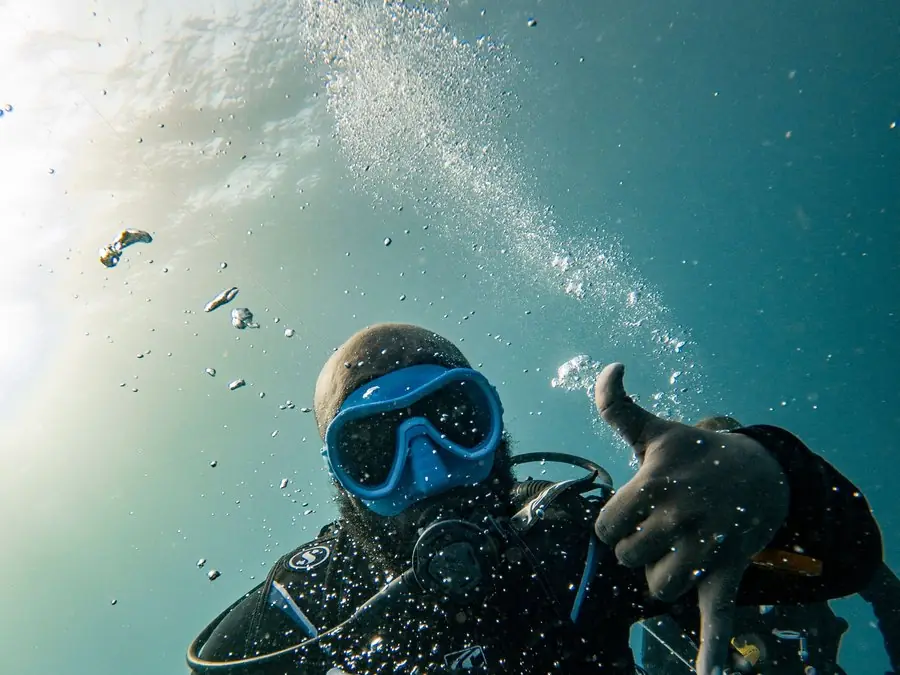 Un buzo bajo el agua levanta el pulgar