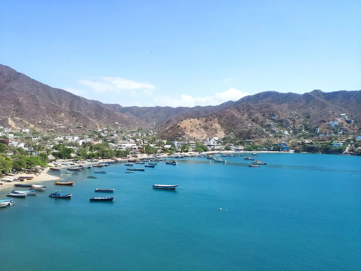 La bahía de Taganga desde el aire, con las lanchas sobre el mar turquesa y las montañas